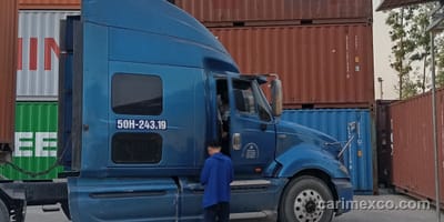Xe đầu kéo của CARIMEX chờ nhận container tại bãi Nhơn Trạch, phía sau là container Hapag-Lloyd xếp tầng